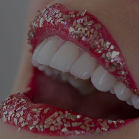 Close up of woman smiling with gold on lips to demonstrate the beginning of how this smile design dental lab can take dentistry to the next level.